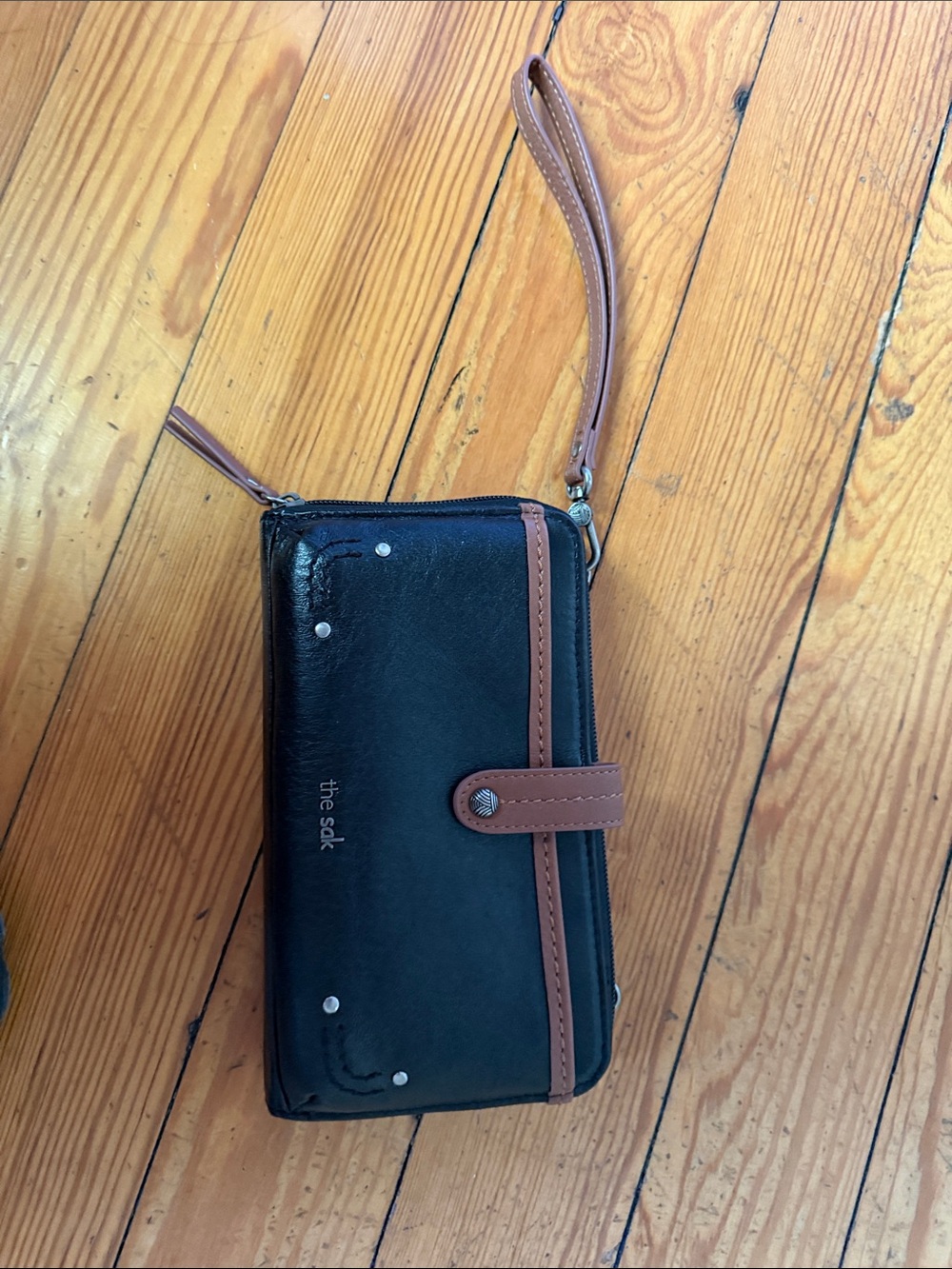 The Sak black and brown wristlet wallet with tan strap and snap